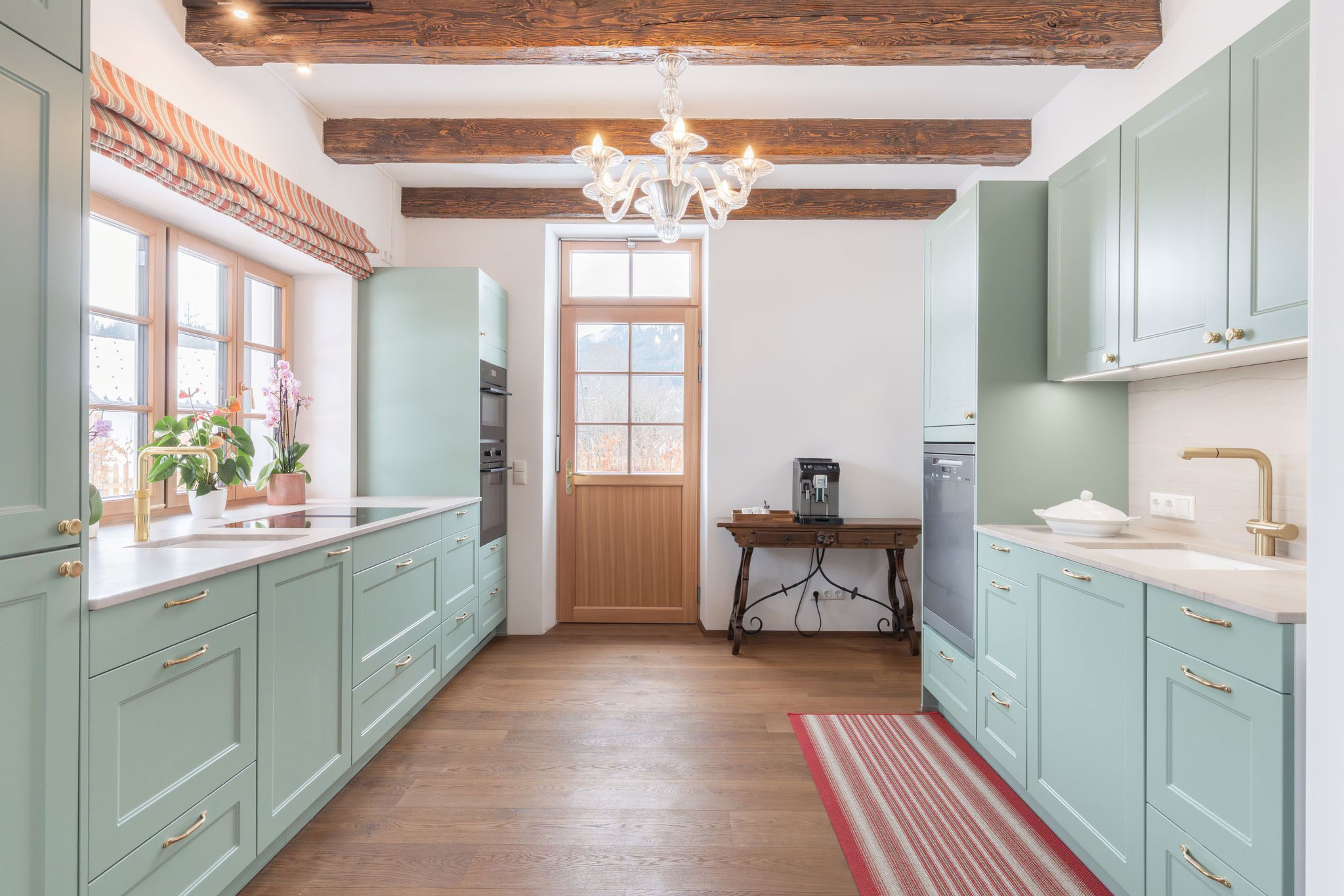 Küche in Mintgrün mit Marmor-Arbeitsfläche, Messing-Armaturen und Holzbalkendecke