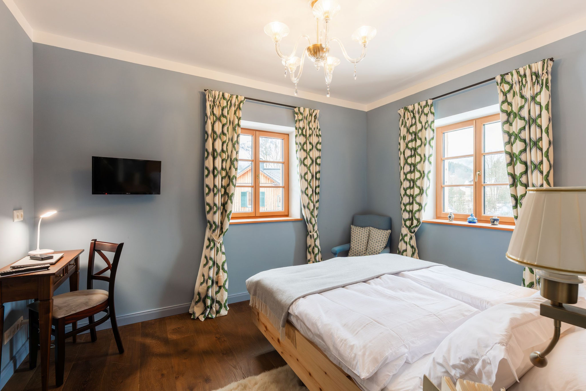 Schlafzimmer in Taubenblau mit Zirbenbett und Schreibplatz am Fenster